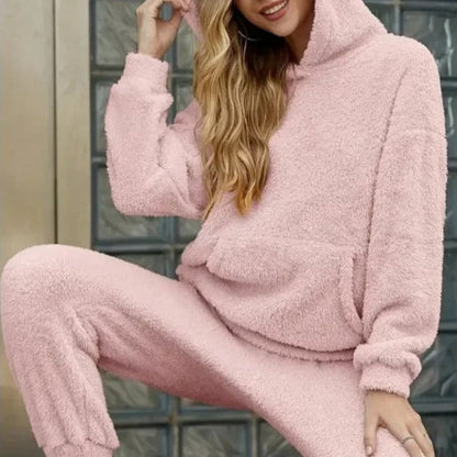 Donna con felpa e pantaloni in pile rosa, seduta davanti a una porta. Abbigliamento comodo e casual, moda autunnale, look accogliente e trendy.