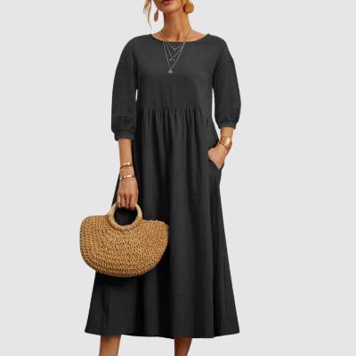 Donna con abito nero lungo, maniche a tre quarti, collane a strati, borsa in paglia intrecciata. Moda elegante, stile casual chic.