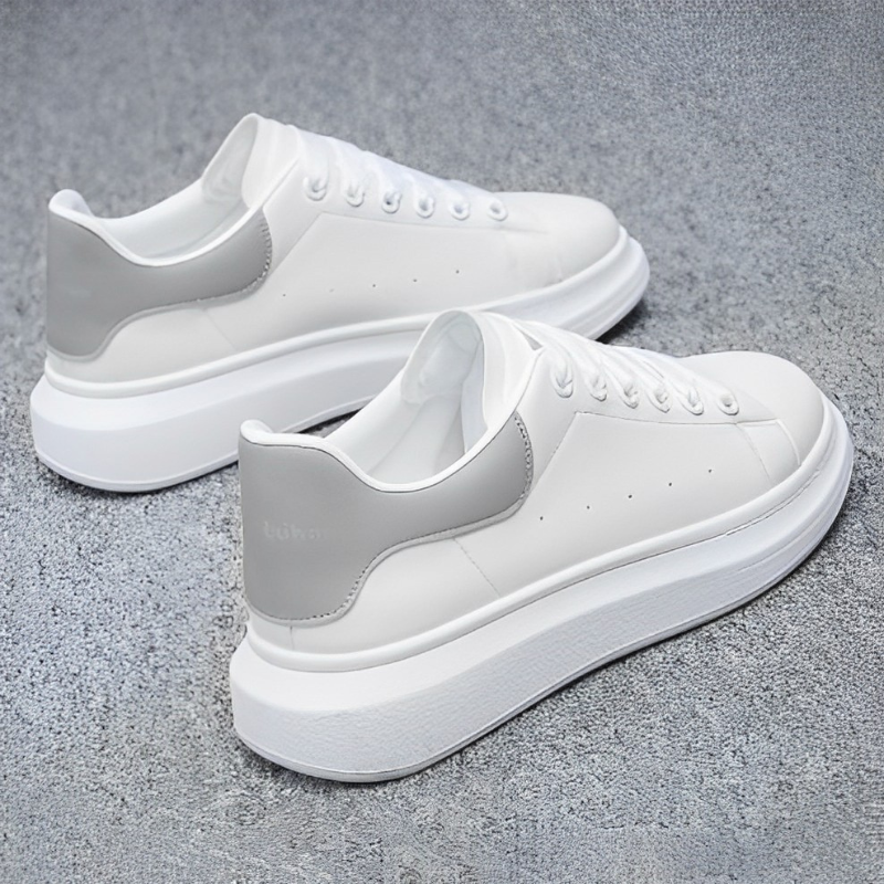 Scarpe da ginnastica bianche con suola spessa, dettagli grigi sul tallone, su sfondo grigio. Design moderno, calzature casual eleganti.