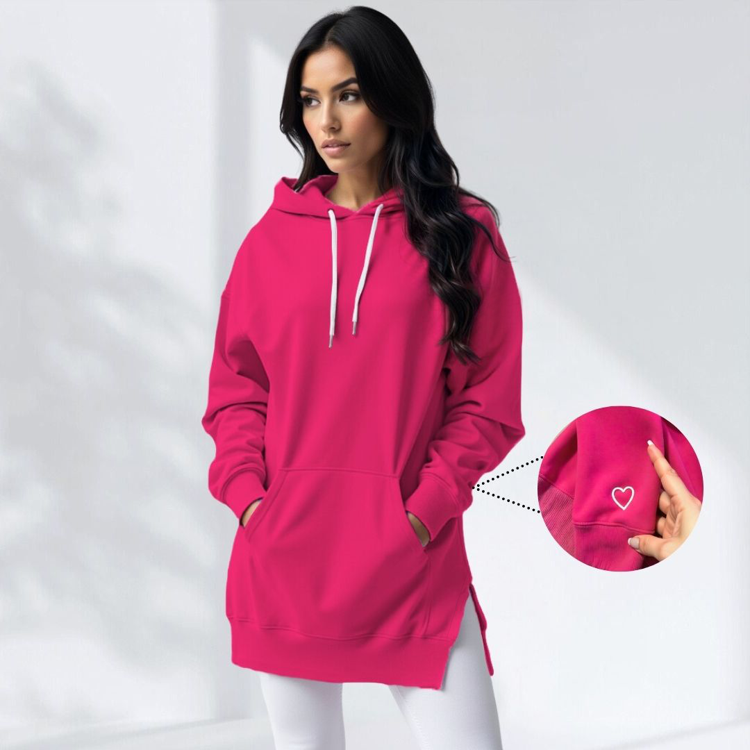 Donna con felpa rosa acceso, cappuccio e tasche, dettaglio cuore ricamato. Moda casual, abbigliamento autunnale, stile urbano.
