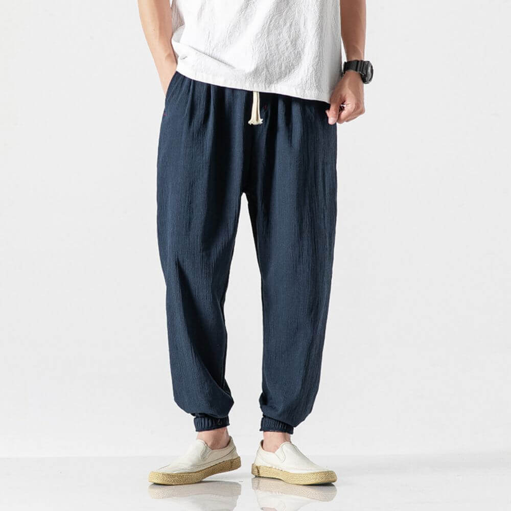 Uomo in pantaloni larghi blu scuro e maglietta bianca, indossa scarpe casual beige. Stile casual maschile, moda estiva, abbigliamento comodo.