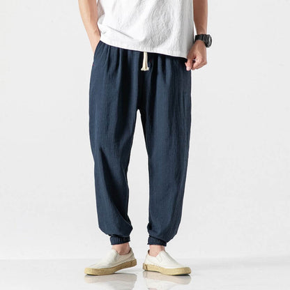 Uomo in pantaloni larghi blu scuro e maglietta bianca, indossa scarpe casual beige. Stile casual maschile, moda estiva, abbigliamento comodo.