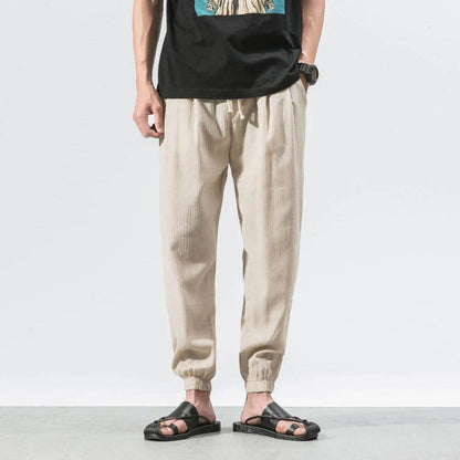 Uomo in pantaloni beige casual, t-shirt nera, sandali neri. Moda estiva maschile, abbigliamento comodo, stile urbano.