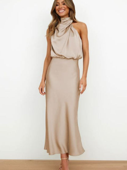Donna in abito lungo beige elegante, senza maniche, con collo alto drappeggiato. Moda femminile, abbigliamento da sera, stile sofisticato.