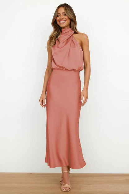 Donna in abito lungo rosa salmone, senza maniche, con scollo all'americana, su sfondo bianco. Moda elegante, abbigliamento femminile chic.
