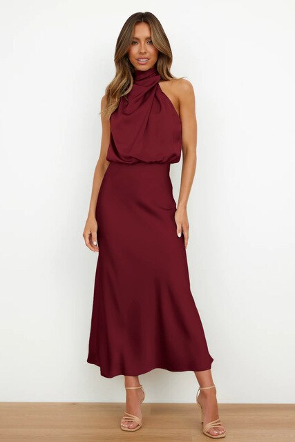 Abito lungo elegante bordeaux con collo alto drappeggiato, indossato da una donna su sfondo bianco. Moda femminile, abbigliamento da sera.