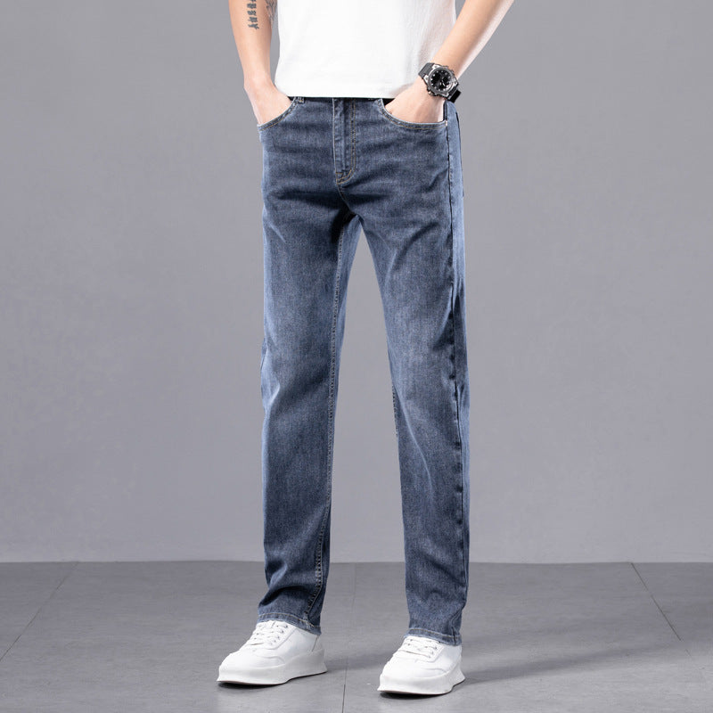 Jeans uomo blu casual, vestibilità dritta, indossati con scarpe bianche su sfondo grigio. Moda maschile, abbigliamento casual.