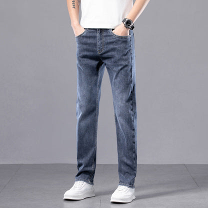 Jeans uomo blu casual, vestibilità dritta, indossati con scarpe bianche su sfondo grigio. Moda maschile, abbigliamento casual.