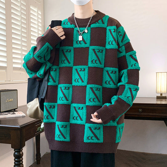 Maglione oversize marrone e verde con motivo geometrico, indossato da una persona in una stanza moderna. Stile casual, moda autunno-inverno.
