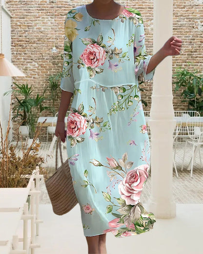 Abito floreale donna, lungo, azzurro, con rose rosa e verdi, maniche a tre quarti. Moda estiva elegante, perfetto per eventi all'aperto.
