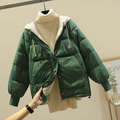 Giacca invernale verde imbottita con cappuccio, indossata sopra un maglione a collo alto color crema. Moda autunnale, abbigliamento caldo e casual.