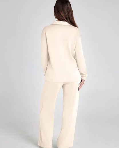 Donna di spalle indossa un completo beige elegante, composto da giacca e pantaloni larghi. Moda femminile, abbigliamento formale, stile minimalista.
