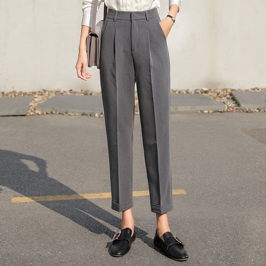 Pantaloni eleganti grigi da donna, taglio dritto, abbinati a mocassini neri e camicia bianca. Moda femminile, abbigliamento formale.