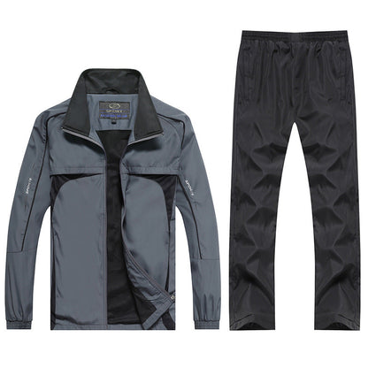 Completo sportivo uomo grigio e nero, giacca con zip e pantaloni coordinati, tessuto impermeabile, ideale per attività all'aperto e fitness.