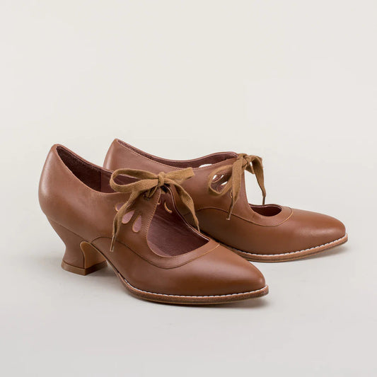 Scarpe da ballo in pelle marrone con tacco medio, lacci decorativi e design vintage. Calzature eleganti per danza e occasioni speciali.