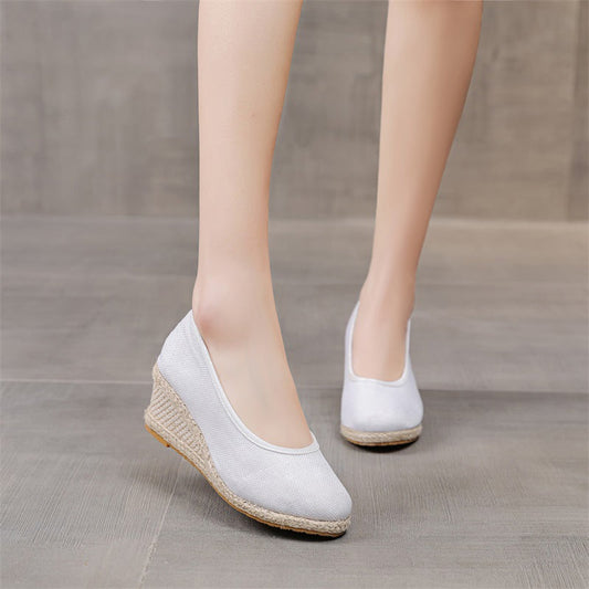Scarpe con zeppa bianche da donna su pavimento grigio, design elegante e moderno, perfette per look casual e formali.