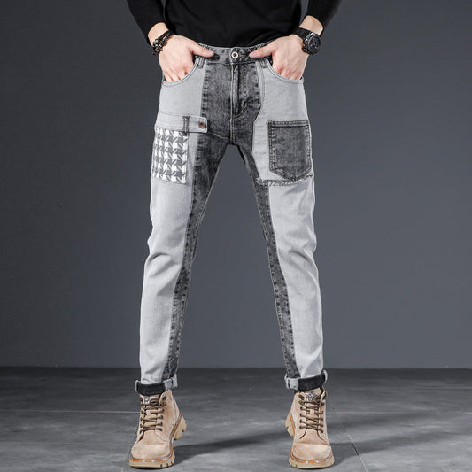 Jeans uomo grigi con design patchwork, tasche multiple e dettagli geometrici, indossati con stivali marroni. Moda casual maschile.
