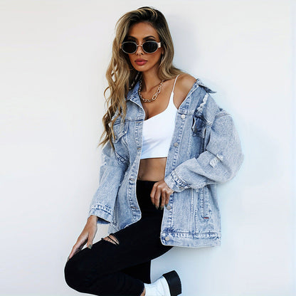 Donna con giacca di jeans oversize, top bianco e pantaloni neri strappati. Indossa occhiali da sole rotondi e collana dorata. Moda casual chic.