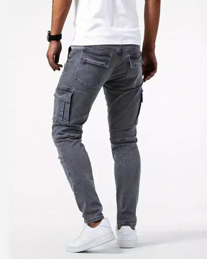 Jeans cargo grigi da uomo, vestibilità slim, tasche laterali, abbinati a scarpe da ginnastica bianche e t-shirt bianca. Moda casual maschile.