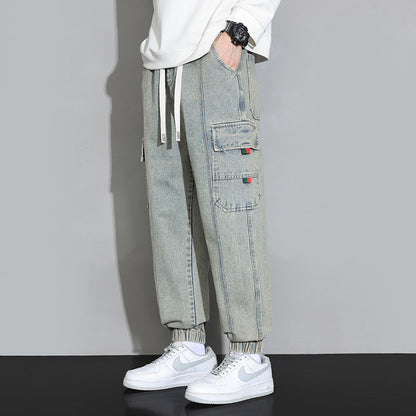 Pantaloni cargo uomo in denim chiaro, tasche laterali, abbinati a sneakers bianche Nike. Stile casual, moda streetwear, abbigliamento trendy.