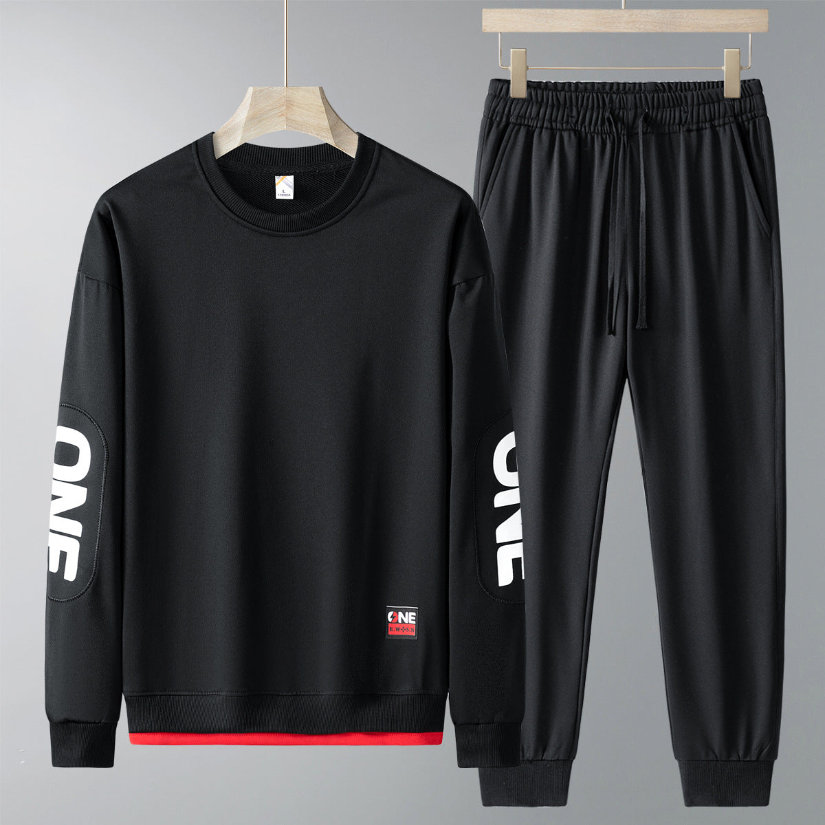 Completo sportivo nero da uomo, felpa e pantaloni con scritta "ONE" sulle maniche. Abbigliamento casual, moda uomo, stile moderno.