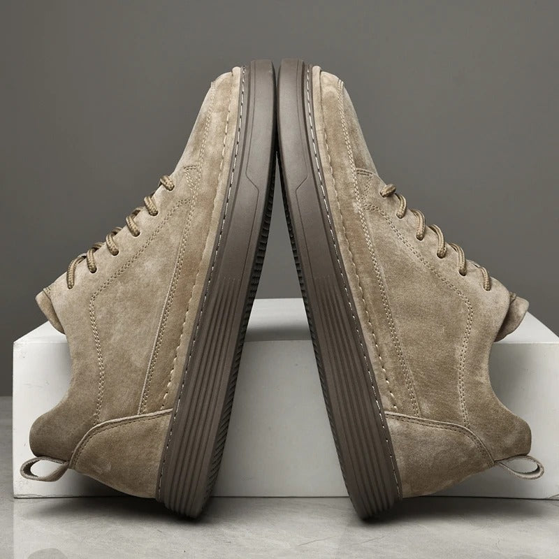 Scarpe da ginnastica beige in pelle scamosciata, suola marrone, design moderno, stile casual, moda uomo, calzature eleganti, sfondo grigio.