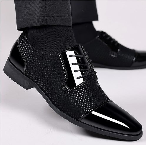 Scarpe eleganti da uomo nere lucide, con lacci e dettagli a trama, indossate con pantaloni scuri. Calzature formali per occasioni speciali.