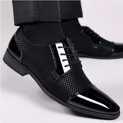 Scarpe eleganti da uomo nere lucide, con lacci e dettagli a trama, indossate con pantaloni scuri. Calzature formali per occasioni speciali.