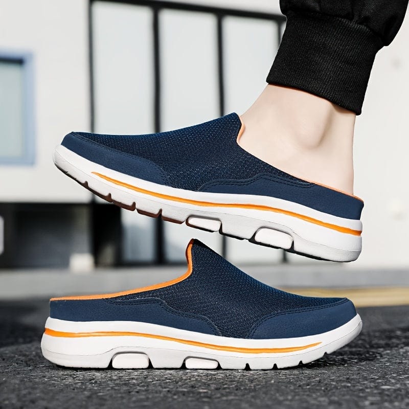 Scarpe slip-on blu da uomo con suola bianca e dettagli arancioni, indossate su strada asfaltata. Calzature casual estive, comode e traspiranti.