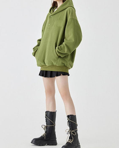 Donna in felpa verde oversize, gonna nera a pieghe e stivali neri alti con lacci. Moda casual autunnale, abbigliamento streetwear femminile.