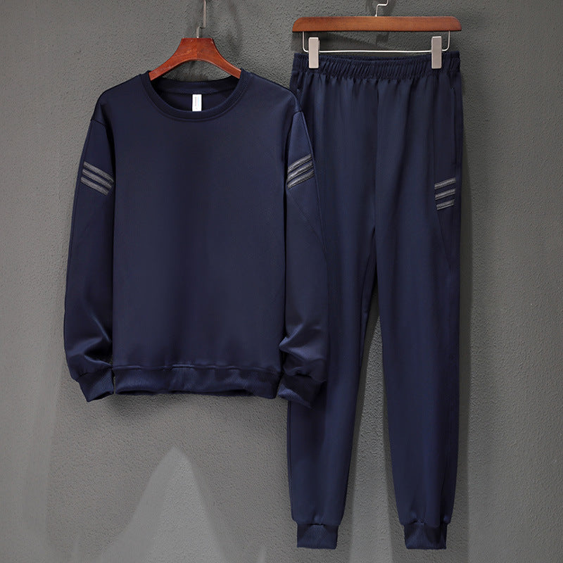 Tuta sportiva blu scuro, composta da felpa e pantaloni con dettagli a righe sulle maniche e tasche, appesa su grucce di legno.