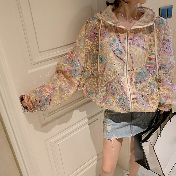Giacca trasparente ricamata con motivi colorati, indossata da una donna con minigonna di jeans. Moda femminile, abbigliamento trendy, stile casual.