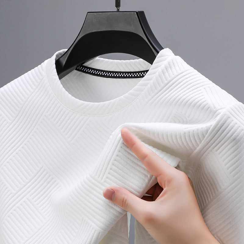 Maglia bianca a trama geometrica su appendiabiti nero, mano che tocca il tessuto. Moda, abbigliamento moderno, texture elegante.