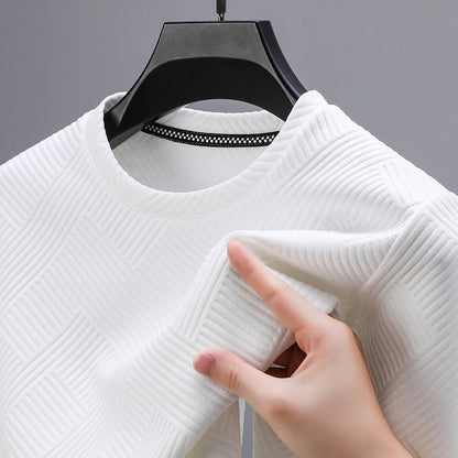 Maglia bianca a trama geometrica su appendiabiti nero, mano che tocca il tessuto. Moda, abbigliamento moderno, texture elegante.