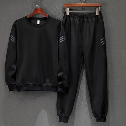 Tuta sportiva nera in poliestere, composta da felpa a maniche lunghe e pantaloni con elastico in vita, appesa su grucce di legno.