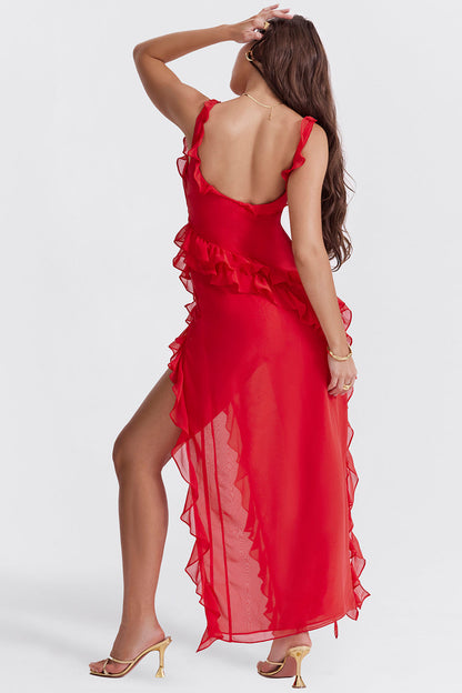 Donna in abito rosso elegante con volant, spacco laterale e sandali dorati. Moda femminile, abbigliamento da sera, stile glamour.