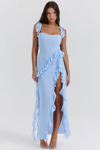 Donna in abito lungo azzurro con volant, spacco laterale e spalline annodate. Elegante vestito estivo, moda femminile, abbigliamento chic.