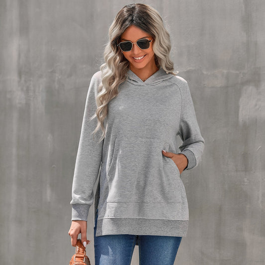 Donna con felpa grigia e occhiali da sole, capelli ondulati, posa sorridente. Moda casual autunnale, stile urbano, comfort quotidiano.