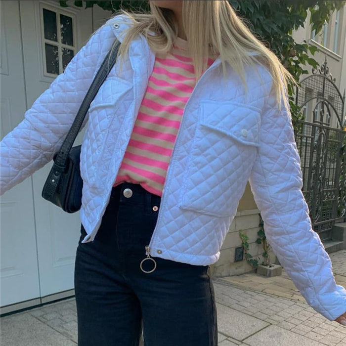 Giacca trapuntata bianca su maglia a righe rosa e bianche, jeans neri, borsa a tracolla nera. Moda casual femminile, look autunnale urbano.