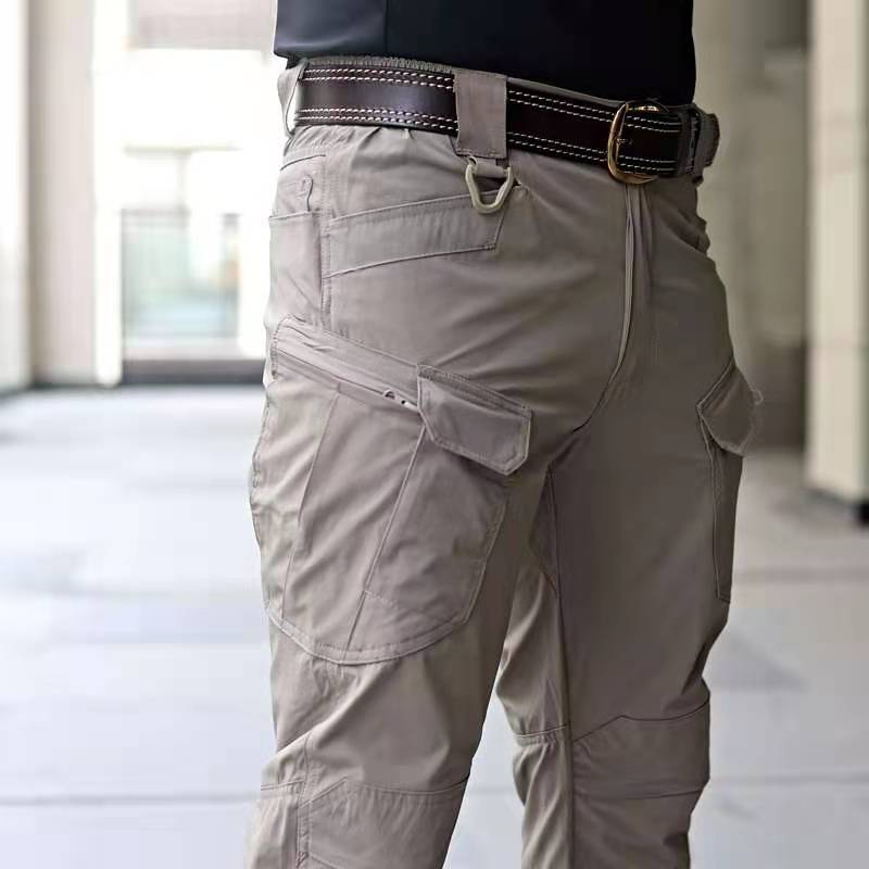 Pantaloni cargo beige da uomo con tasche multiple, cintura in pelle marrone, moda casual urbana, abbigliamento maschile funzionale e versatile.