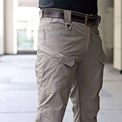 Pantaloni cargo beige da uomo con tasche multiple, cintura in pelle marrone, moda casual urbana, abbigliamento maschile funzionale e versatile.