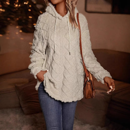 Donna con felpa in pile bianco, cappuccio e tasche, indossa jeans aderenti. Look casual e accogliente, perfetto per l'autunno.