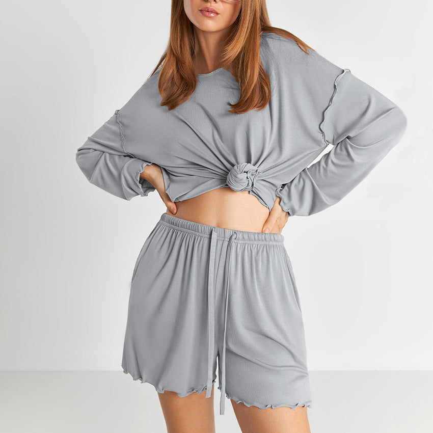 Donna con pigiama grigio a maniche lunghe e pantaloncini, moda loungewear, abbigliamento comodo per casa, stile casual e rilassato.
