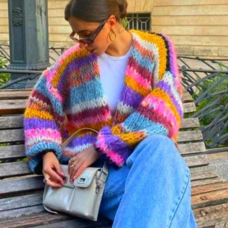 Donna con cardigan a righe colorate, jeans larghi e borsa beige. Moda autunnale, stile casual chic, accessori trendy.