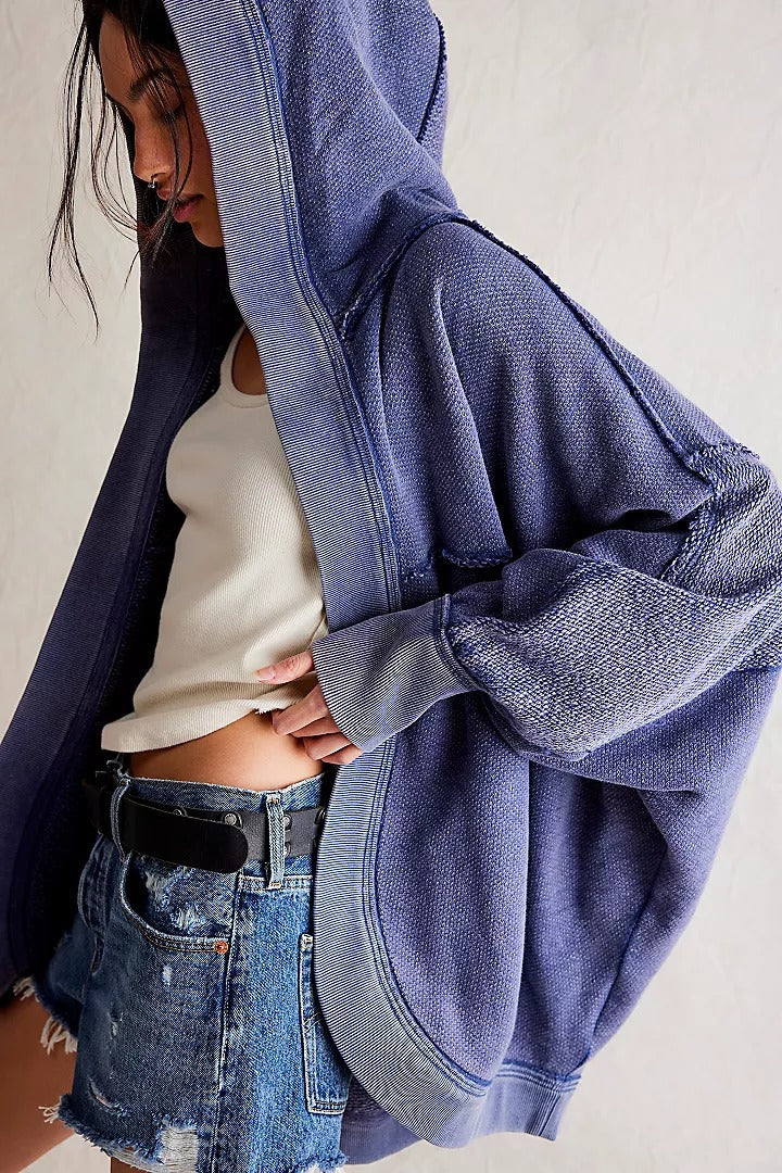 Donna con felpa oversize blu, canotta bianca e shorts di jeans. Moda casual, abbigliamento streetwear, stile urbano.