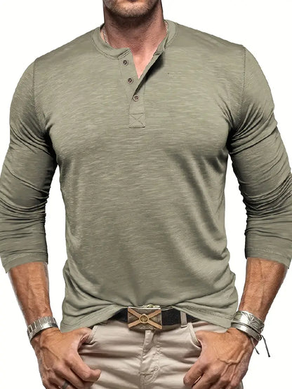 Uomo con maglia verde oliva a maniche lunghe e bottoni, pantaloni beige, cintura con fibbia decorativa, bracciali in metallo. Moda casual maschile.