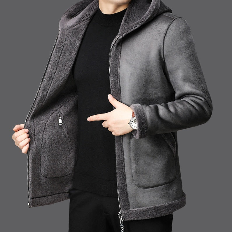 Giacca invernale uomo grigia con cappuccio, interno in pelliccia sintetica, chiusura a zip, indossata su maglione nero. Moda maschile elegante.
