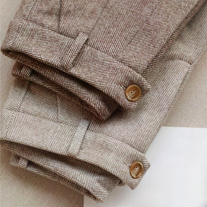 Pantaloni in lana a spina di pesce marrone chiaro, piegati, con bottoni in legno. Tessuto elegante e classico, ideale per moda autunnale.