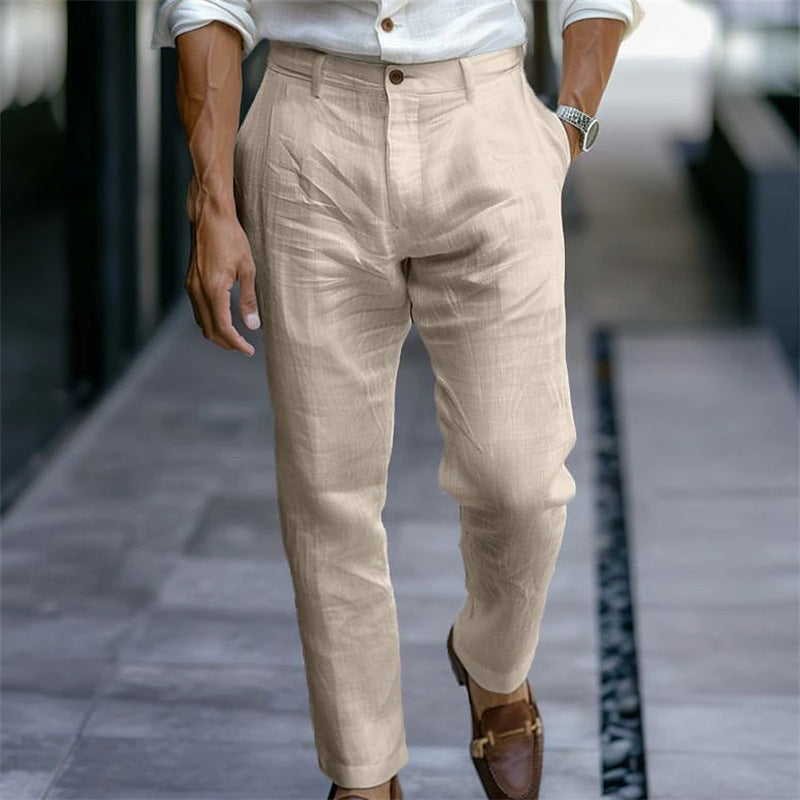 Uomo in pantaloni di lino beige, camicia bianca, mocassini marroni, cammina su marciapiede urbano. Moda maschile elegante, abbigliamento estivo.