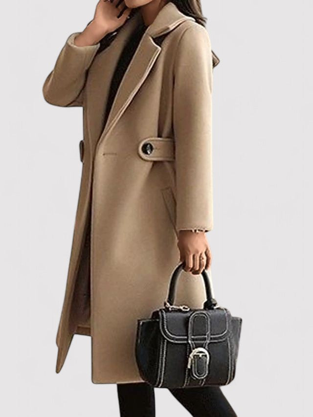 Cappotto beige elegante donna, lungo con cintura, abbinato a borsa nera con fibbia. Moda autunnale, abbigliamento femminile chic.